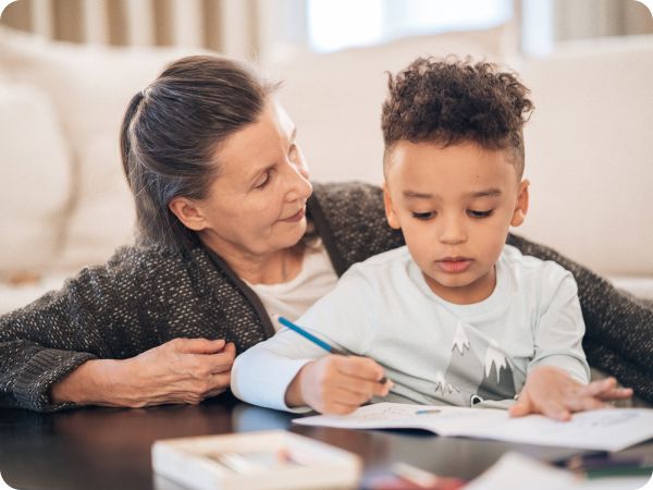 Photo of an elderly woman looking at a young boy with a pencil and booklet