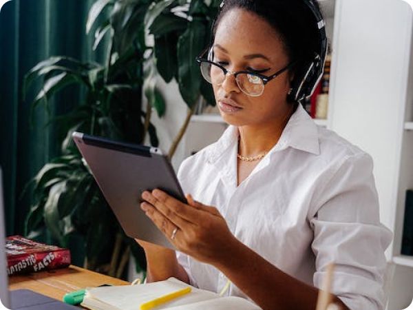 Photo of a woman wearing headphones and using a tablet