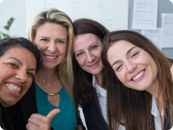 Photo of the heads and shoulders four women leaning in together